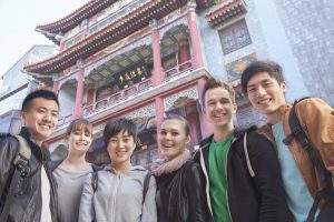 Group of young people with Chinese architecture in background, portrait.